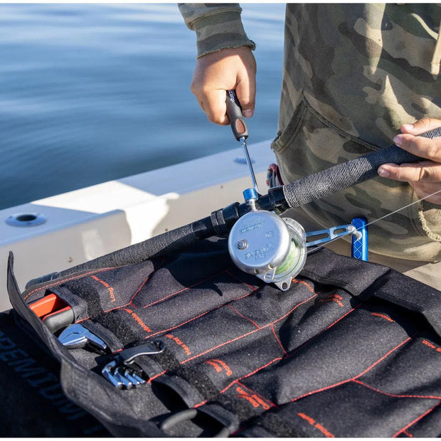 Angler repairing a fishing reel on a boat with a screwdriver from the open BoxoUSA Boat Roll