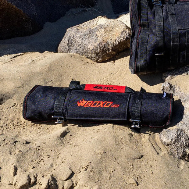 BoxoUSA 28-Piece SAE Tool Roll rolled closed on sand beside an off-road tool bag