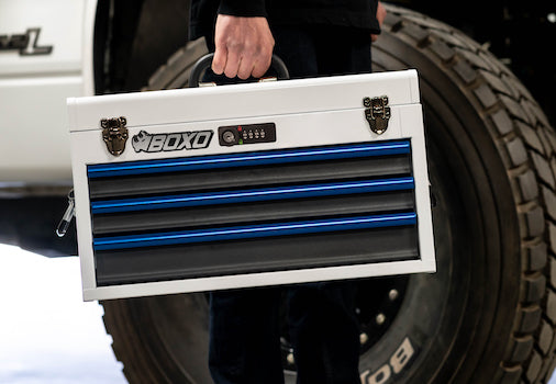 White Boxo Hand Carry toolbox with blue drawer handles being carried to a job site