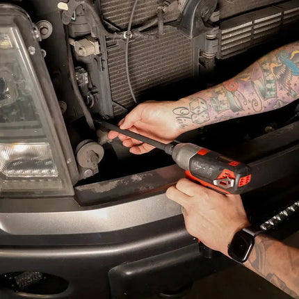 Technician driving a BoxoUSA universal impact extension socket with a cordless impact wrench behind a truck grille