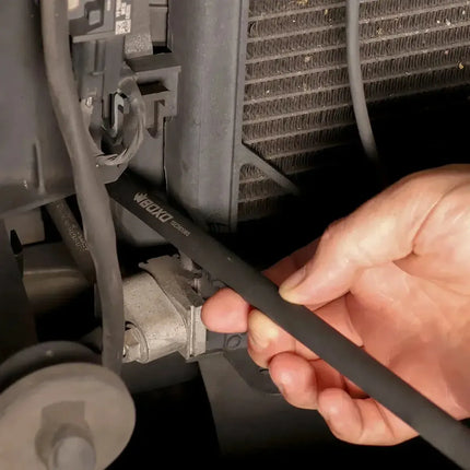 Technician guiding a BoxoUSA 12 inch universal impact extension socket toward a fastener behind a vehicle bumper