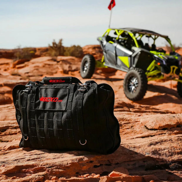 BoxoUSA Off-Road Bag on red rock with a side-by-side in the background
